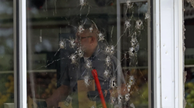 Damage can be seen to a front window as law enforcement officers work the scene of a shooting at the Mad Butcher grocery store in Fordyce, Ark., June 21, 2024.