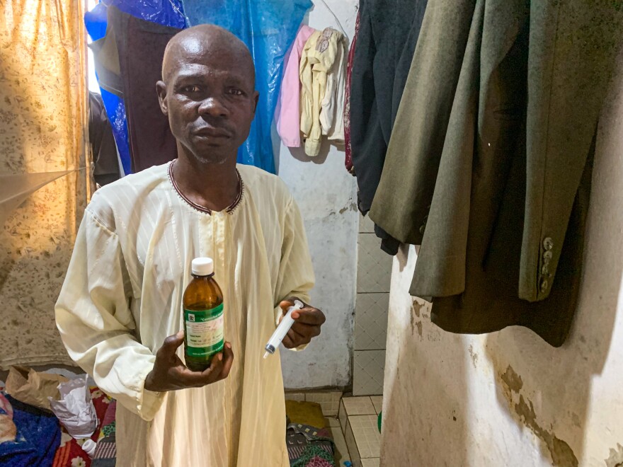 Ronald Mutyaba, an auto mechanic, at his home in Kampala, Uganda. Mutyaba is HIV positive and has developed Karposi sarcoma, a type of cancer that often affects people with immune deficiencies. He is holding a bottle of the liquid morphine that nurses from the nonprofit group Hospice Africa have prescribed to help control the pain caused by his illlness.