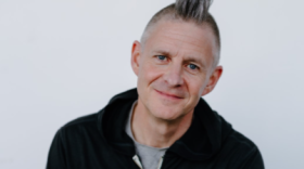Man smiles into camera with a great mohawk haircut.