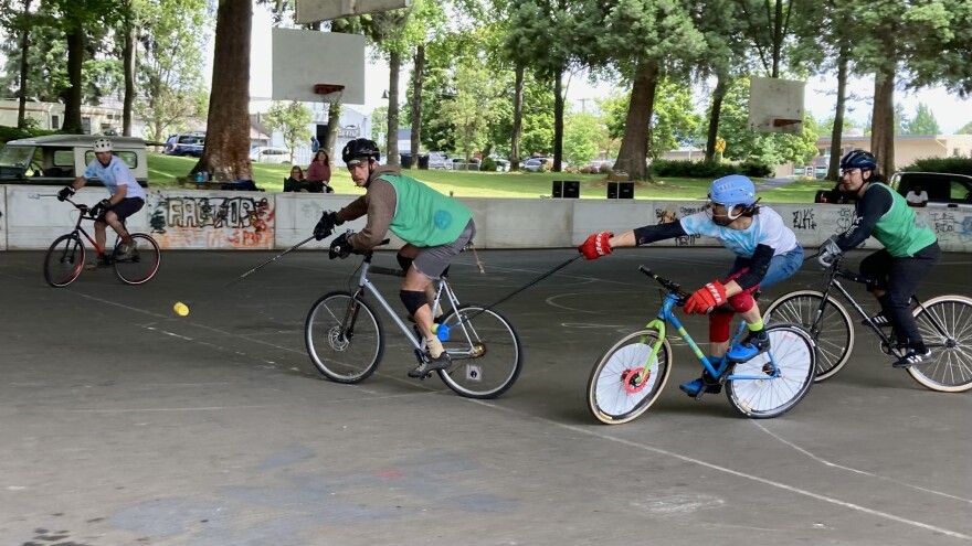  A group of bike polo players pass a ball.