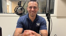Mike Escobar smiles for a photo inside a sound booth.