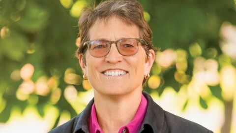 A person with glasses smiles at the camera. 