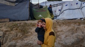 A man carries a child in a camp outside the refugee camp of Moria, in the northern Greek island of Lesbos on September 25, 2018. (Aris Messinis/AFP/Getty Images)