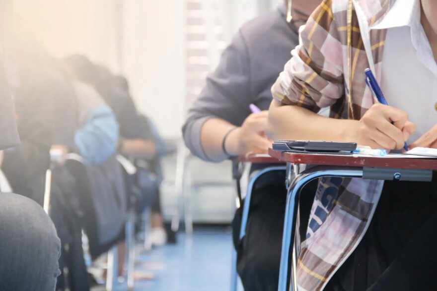 Blurred-out photo  kids in a classroom, zeroing in on their arms and holding pens