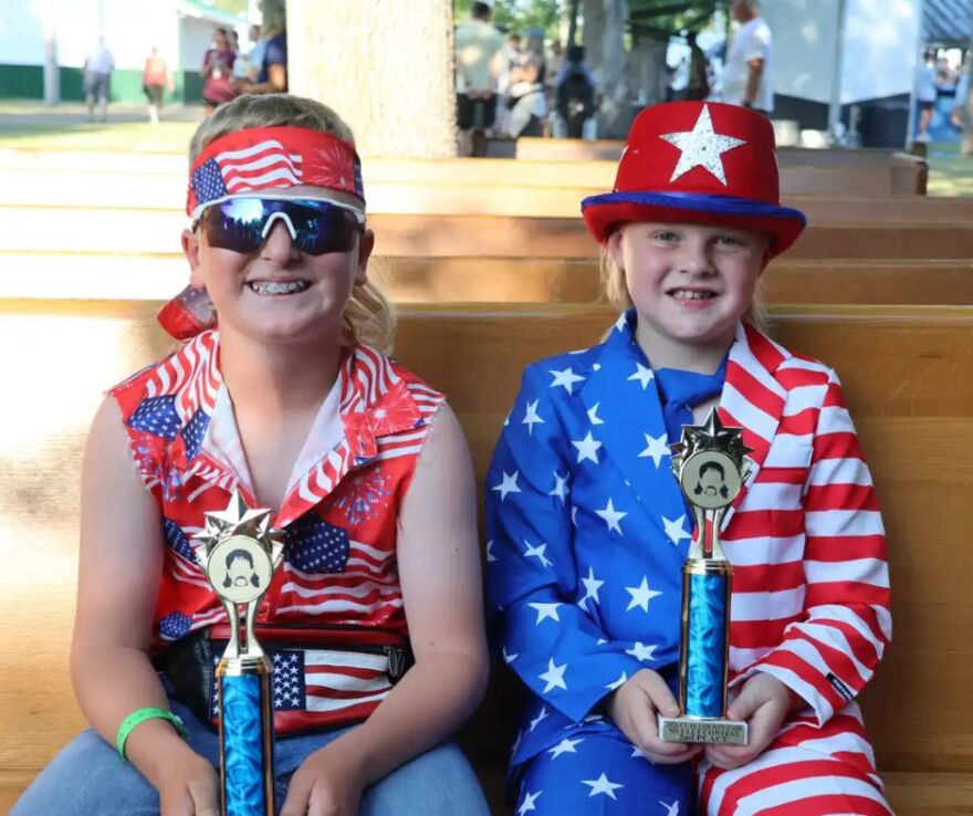 Reed Moszer (left) and Paul Maier hold up the trophies they won at the mullet pageant at the Clay County Fair in Barnesville on July 9 | MPR News