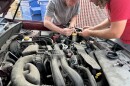 Two volunteers replace headlights on a vehicle at the light repair clinic, Aug. 4, 2026.