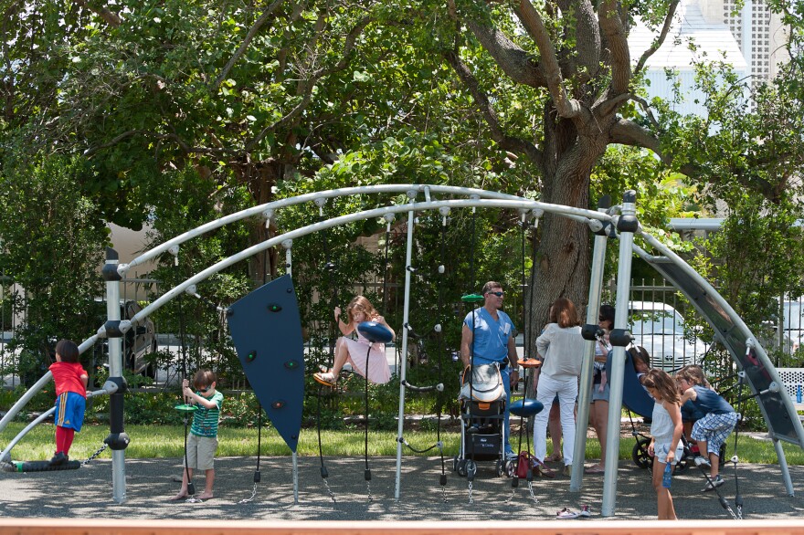 Children play at the 1814 Brickell Park, a new park that features benches, a paved path and a monument made of a girder from the World Trade Center.