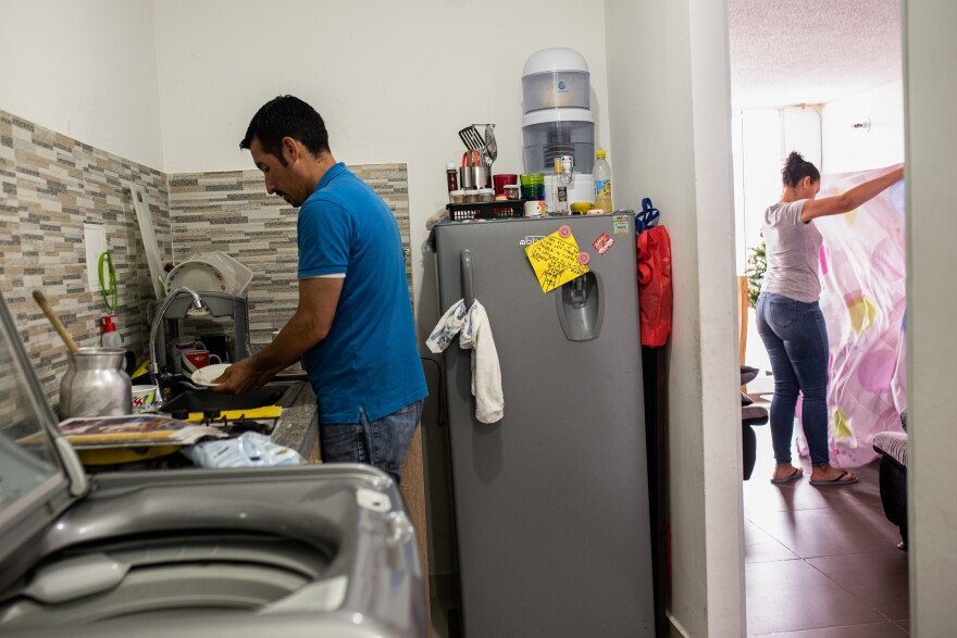 Ferley Sáenz and his wife, María Alejandra López, now divide up household chores. Here, Sáenz washes the dishes while López tidies up the living room.