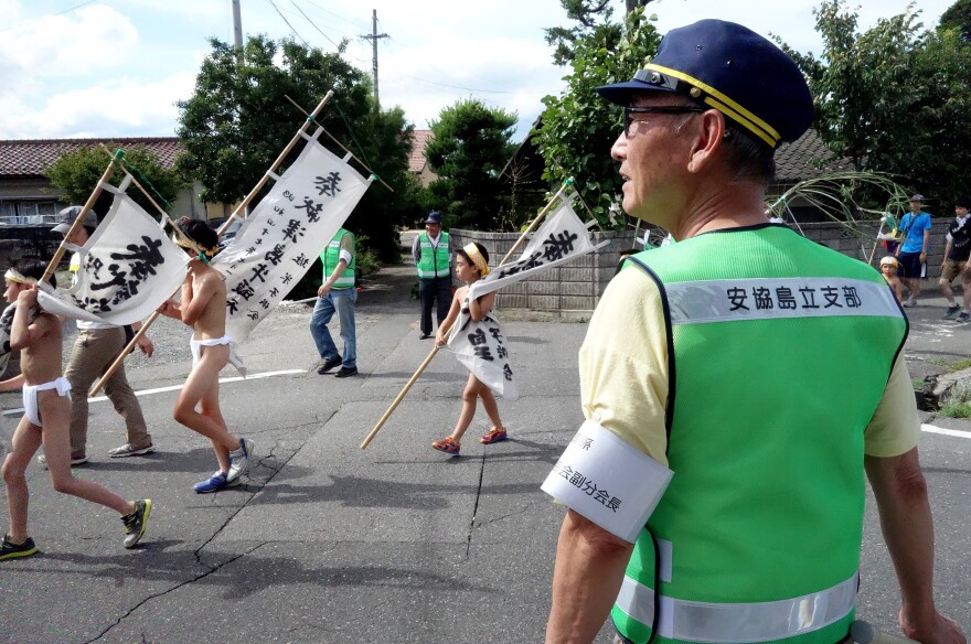 Locals volunteer as crossing guards for the parade through town in Nagano Prefecture. The boys walk about a mile in sweltering July heat.