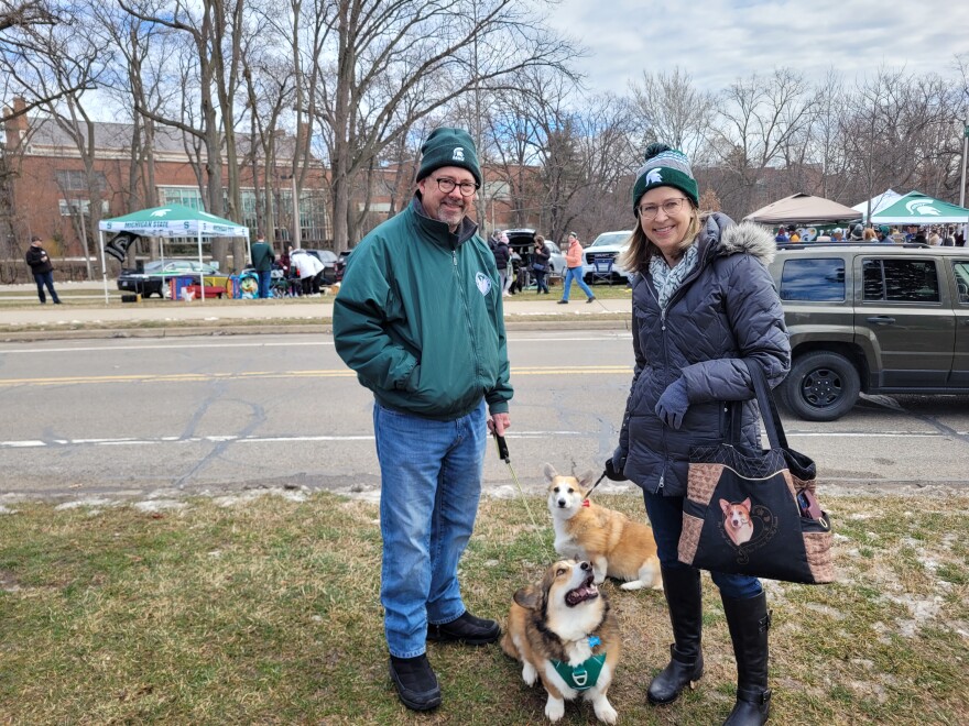 Patti Horne and her husband smiling with two corgis on leashes