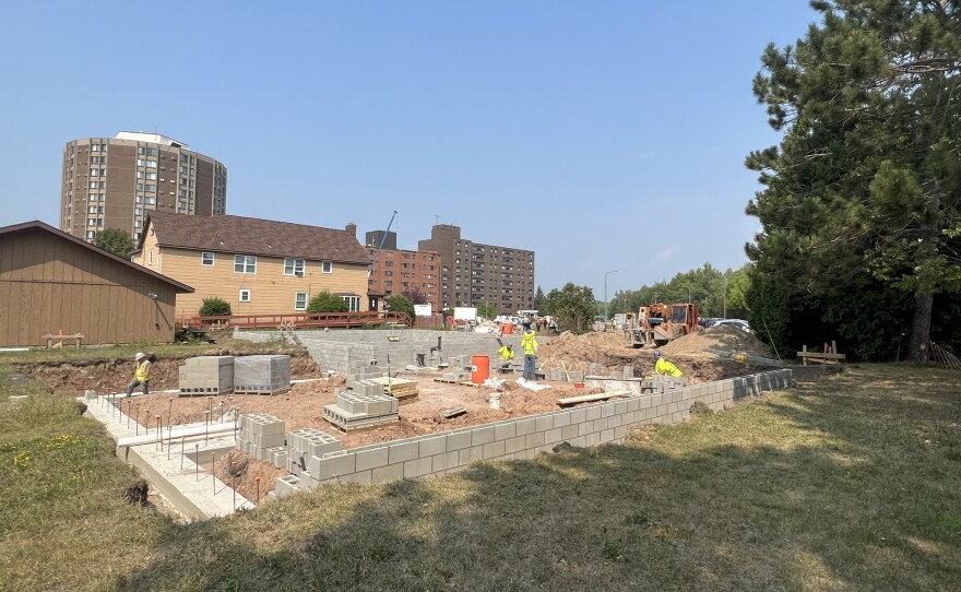 A work site with an area cleared for a new building. Concrete bricks are stacked and construction workers are working.