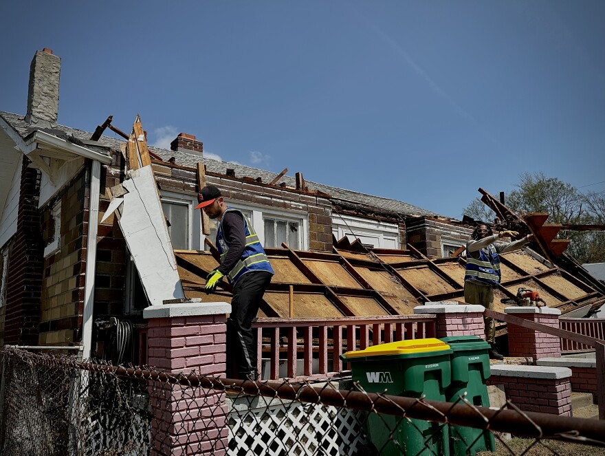 Workers clear debris from a storm-damaged home in kansas city kansas