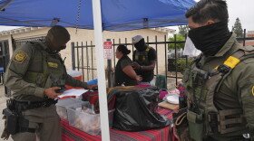 A woman is detained by U.S. Border Patrol agents outside a Home Depot Friday, Aug. 15, 2025, in Los Angeles. (AP Photo/Gregory Bull)