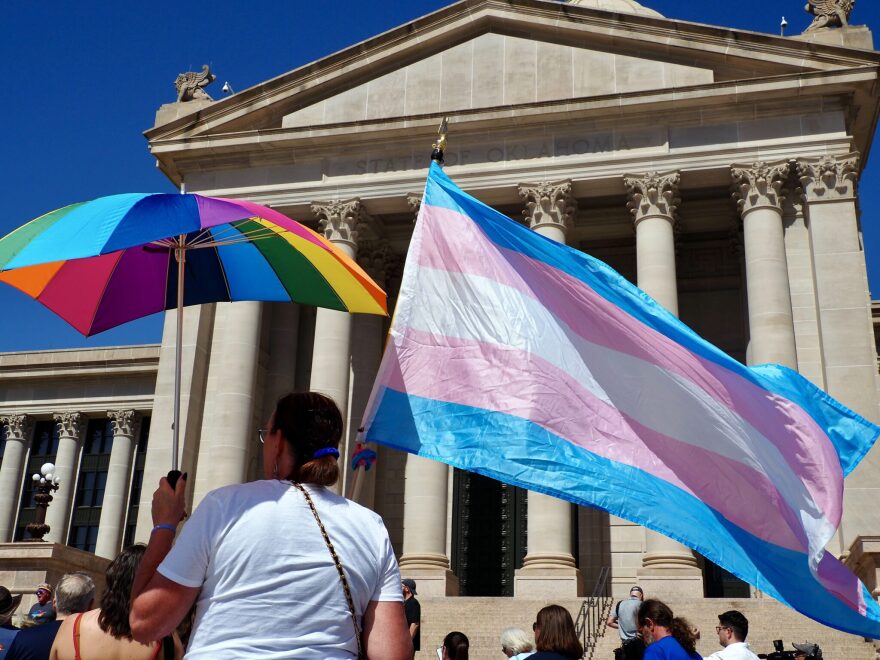 A person holds a transgender pride flag and a rainbow umbrella during a rally outside the Oklahoma State Capitol in Oklahoma City on March 14, 2024.