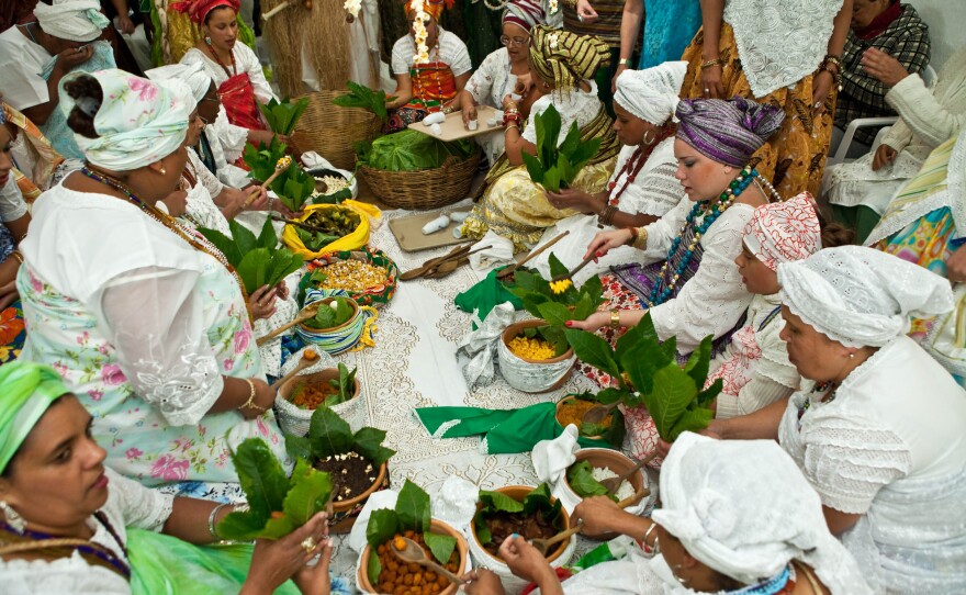People serve sacred food at the Olubaje party. The food is wrapped in leaves from the castor oil plant.