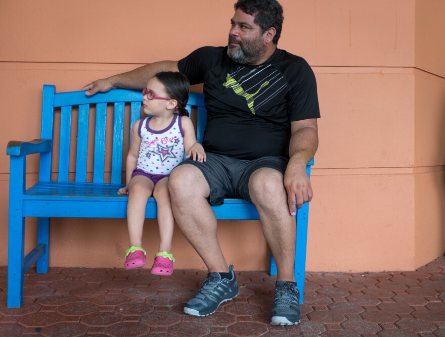 Angelica Alicea, 3, and her grandfather Julio Alicea wait outside the San Jorge Children's Hospital.