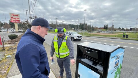 Thane White, a solid waste worker for the city of Tacoma, shows Tacoma city council member John Hines, one of the city's new trash cans. The city is getting 120 new trash cans this year.