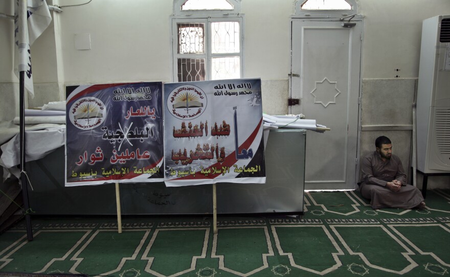 An Egyptian man waits to join afternoon prayers at the mosque used as Gamaa al-Islamiya's headquarters in Assiut, southern Egypt. The banners feature slogans such as "we are against violence and destruction" and "shame to thugs."