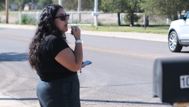 A woman stands beside the street leading to National Beef Tuesday, blowing a whistle and warning workers of federal immigration agents.