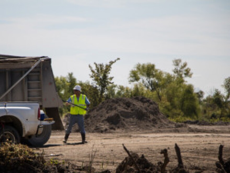 A worker brushes dusty mine waste off a truck before it exits the contaminated site.