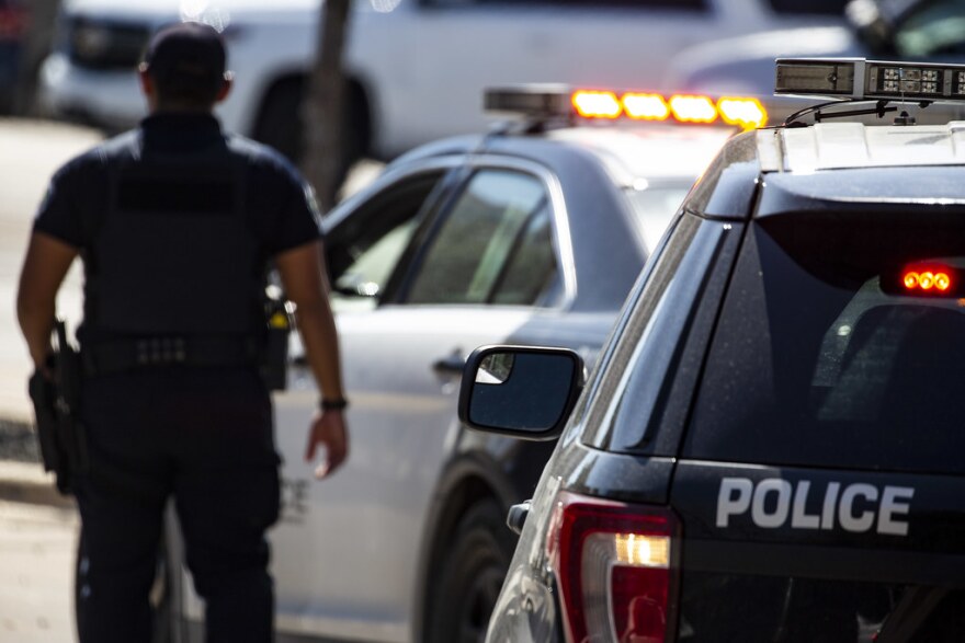 An Austin police officer walks by a line of police cars.