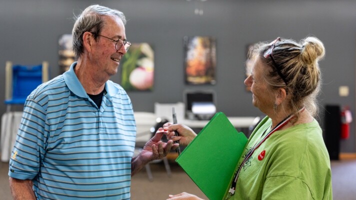 Dave Tanner takes an "I Voted" sticker from election judge Cathy Dietrich at Woodrow Town Hall on Primary Election Day, Aug. 11, 2026.