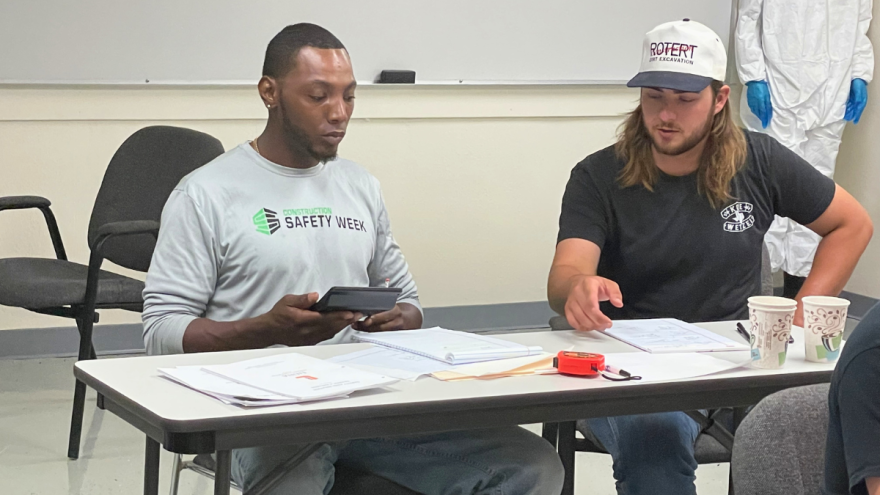 Two apprentices work through coursework during a construction trades training session.
