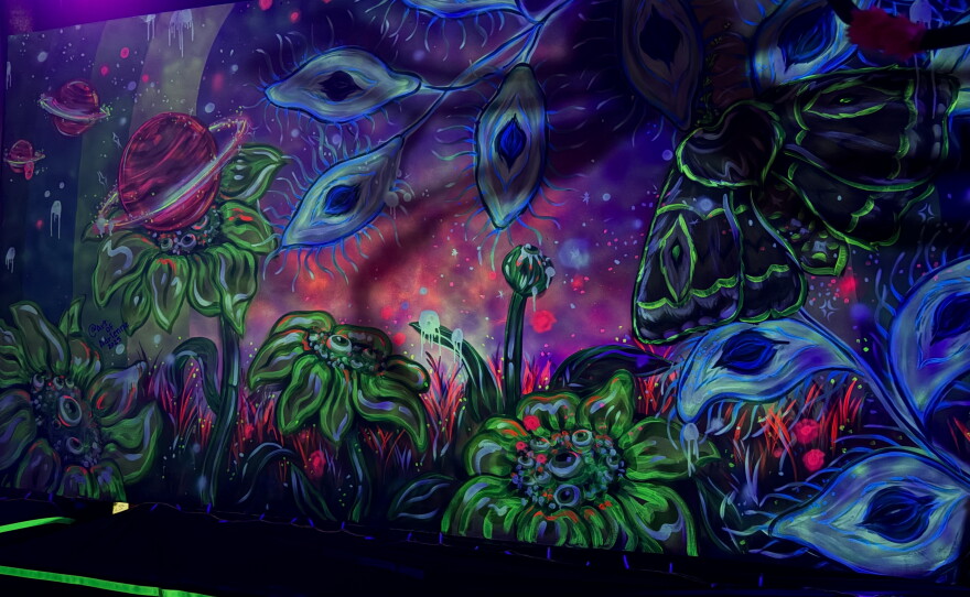 A wall painted with flowers and eyes.