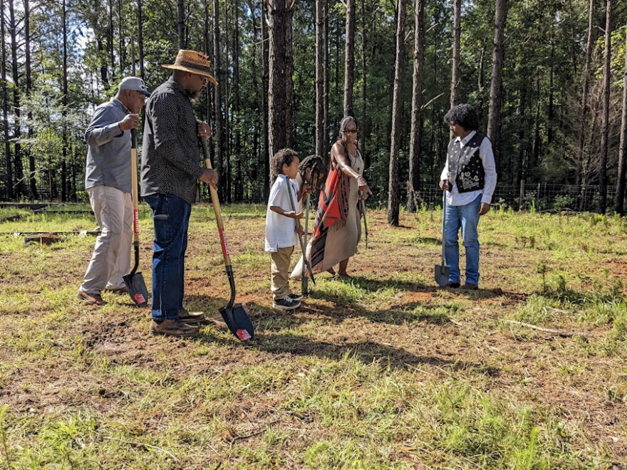 Teresa Ervin-Springs points to where to dig shovels as she stands next to her two mentors, her grandsons and husband Kevin Springs on June 19, 2023, in McCool, Mississippi.