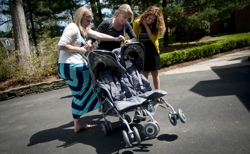 Costello's oldest sister, Megan Gipson (center), teaches Costello and Morales how to fold a twin-baby stroller in the family's driveway.