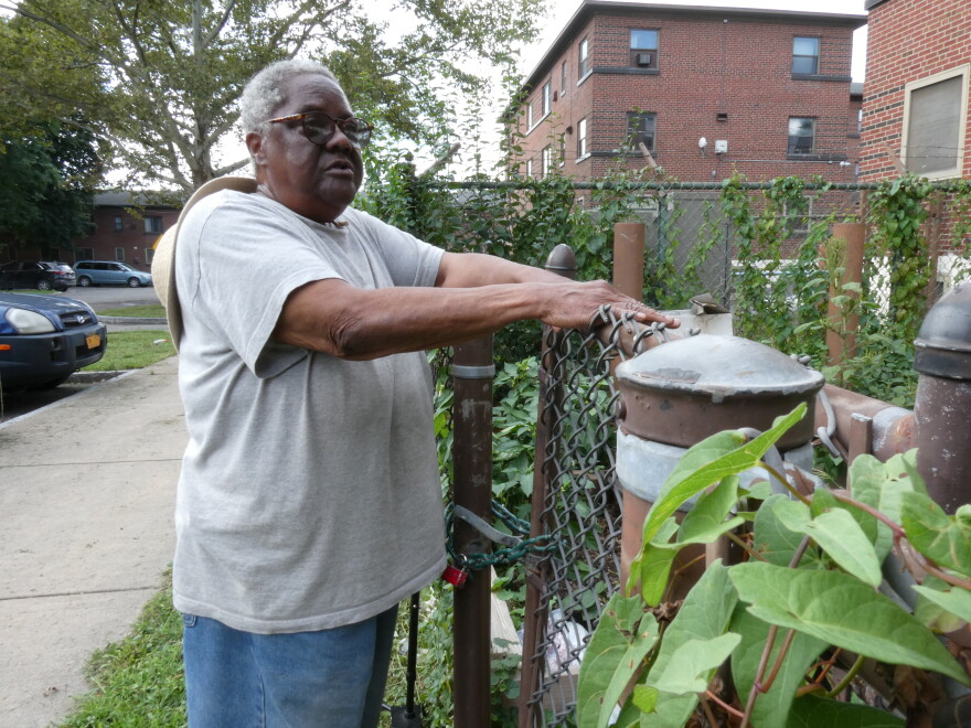 Wilson rests against the gate of the community garden that she helps tend to. Without hearing aids, Wilson fears for safety as she struggles to keep her balance.