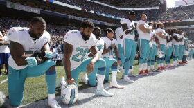 From left, Miami Dolphins' Jelani Jenkins, Arian Foster, Michael Thomas, and Kenny Stills, kneel during the singing of the national anthem before an NFL football game against the Seattle Seahawks in Seattle, on Sept. 11, 2017.