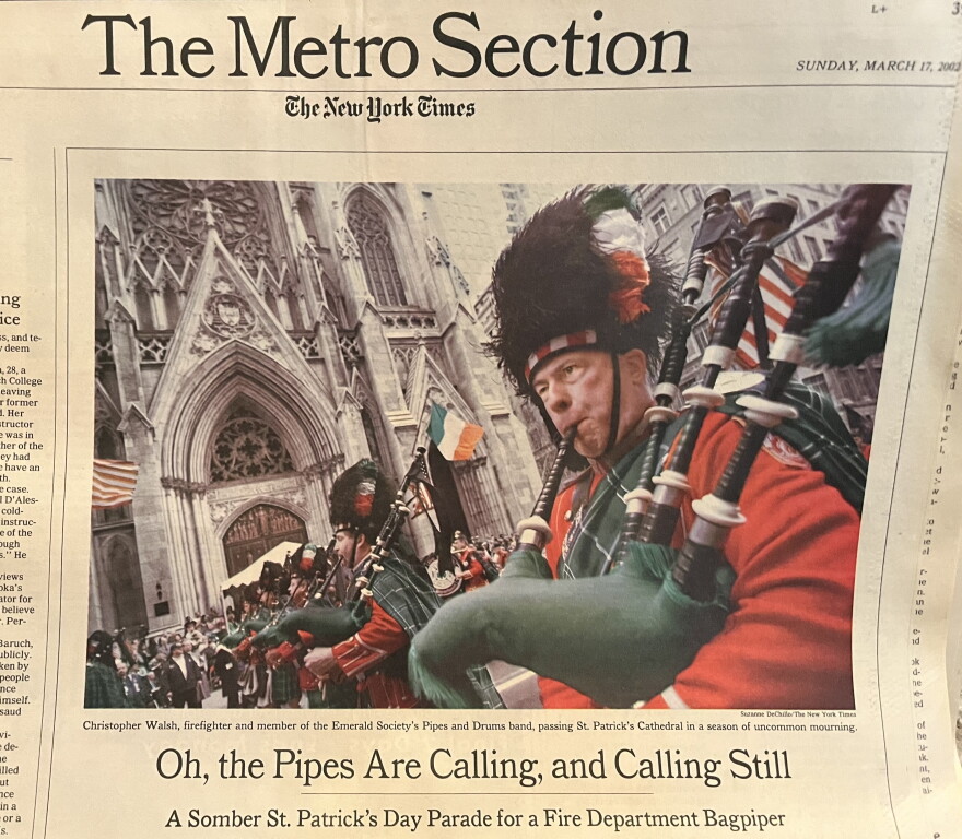 A yellowing newspaper shows a color photo of bagpipers in red playing as they march by St. Patrick's Cathedral