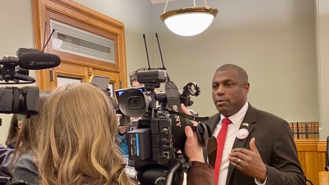 a man speaks into several TV cameras