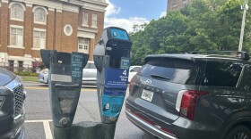 A Close-up of parking meters in downtown Athens. One of them is missing a head, the other has instructions on how to use a new parking app to pay parking fees.