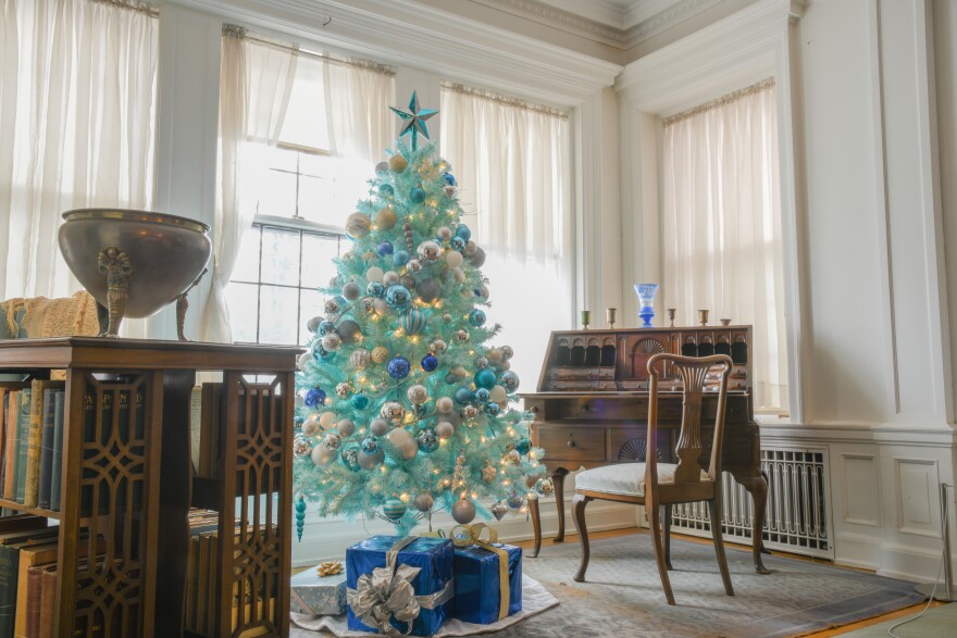 A light blue Christmas tree in a white-lit room surrounded by ornate furniture