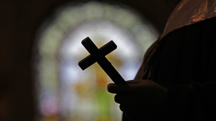 A silhouette of a crucifix framed by a stained glass window