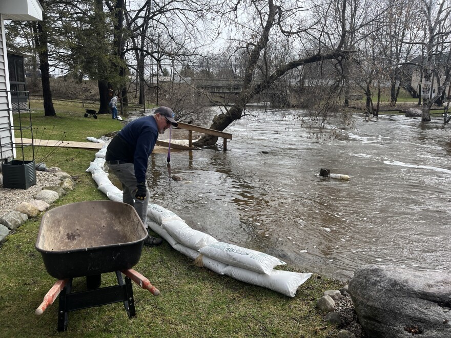 Fred Chacon, Bellaire resident of 12 years, places sandbags between his house and the Intermediate River, just downstream of the Bellaire Dam. (Photo: Claire Keenan-Kurgan/IPR News)