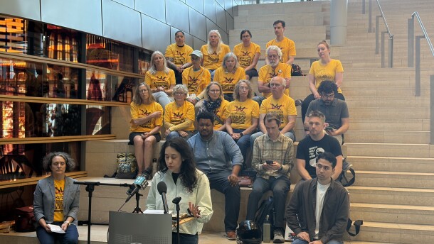 A group of activists stand behind a podium for a press conference on the steps inside Seattle City Hall. 