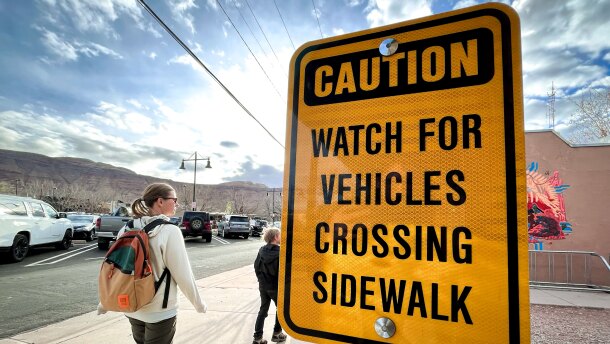 Pedestrians pass a crosswalk caution sign in Moab, Utah, March 14, 2025.