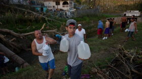 People carry water in bottles retrieved from a canal due to lack of water following passage of Hurricane Maria, in Toa Alta, Puerto Rico, on Sept. 25, 2017. (Hector Retamal/AFP/Getty Images)