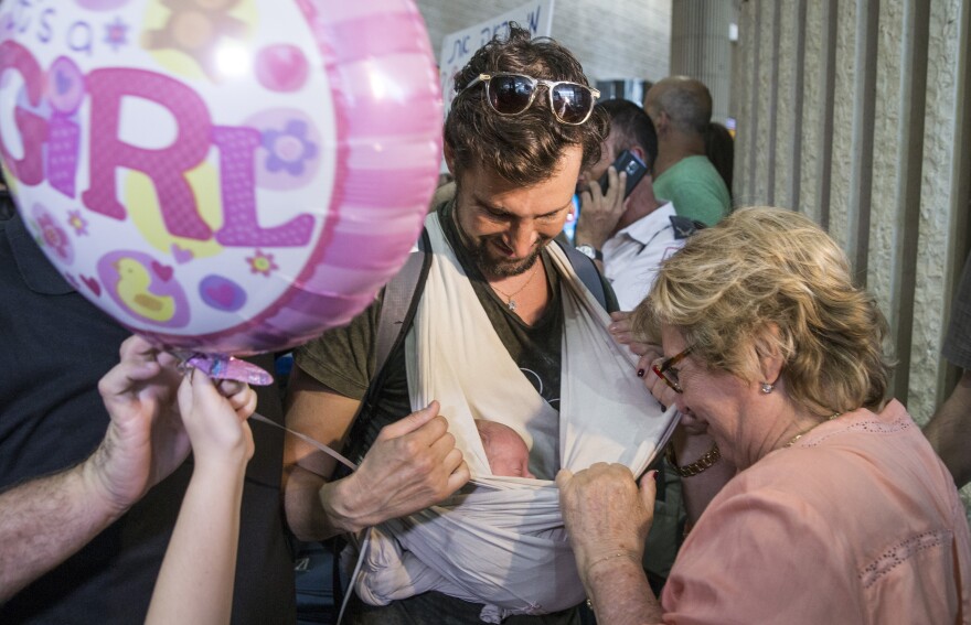 An Israeli man carries his newborn baby, who was born to a surrogate mother in Nepal, as he arrives at Ben Gurion airport near Tel Aviv on April 28, after a massive earthquake hit the Himalayan nation. Israel was criticized for evacuating the babies and Israeli parents who had come to pick them up — but leaving the babies' mothers and other pregnant Nepali surrogates behind.