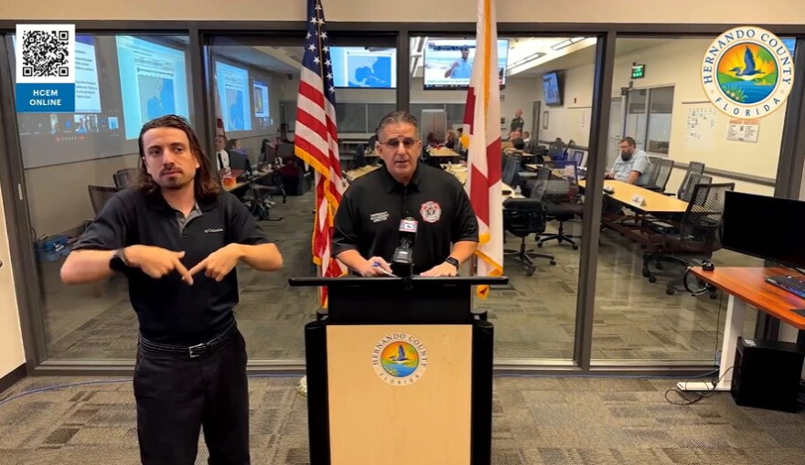 Man speaking at a podium with a sign language interpreter to the left