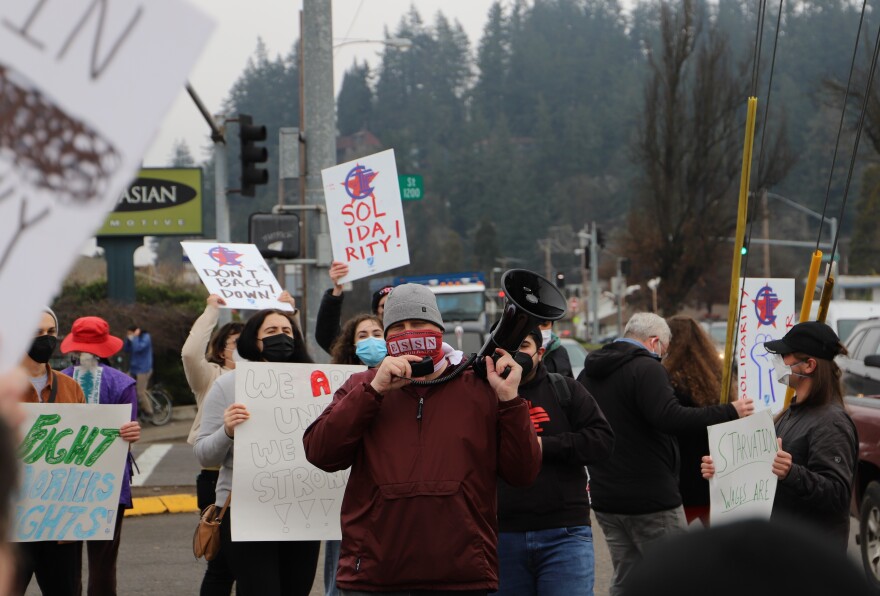 Lonnie Douglas (center, with bullhorn) of Eugene-Springfield Solidarity Network leads chants outside the Starbucks store at Franklin and Villiard today.