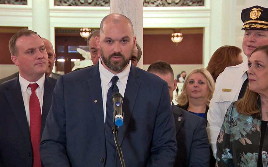 Kyle Gilmartin speaks at the Pennsylvania State Capitol on Monday, May 4, 2026 about proposed legislation to strengthen penalties for individuals who attempt to murder a law enforcement officer and cause serious bodily injury. Gilmartin, a Scranton Police Department detective, survived a 2024 ambush in which he was shot twice in the head. State Sen. Lisa Baker, listening at right, was a co-sponsor of Senate Bill 1284, known as Detective Kyle Gilmartin’s Law, which passed the state Senate Monday by a 41-8. It now heads to the state House for consideration.