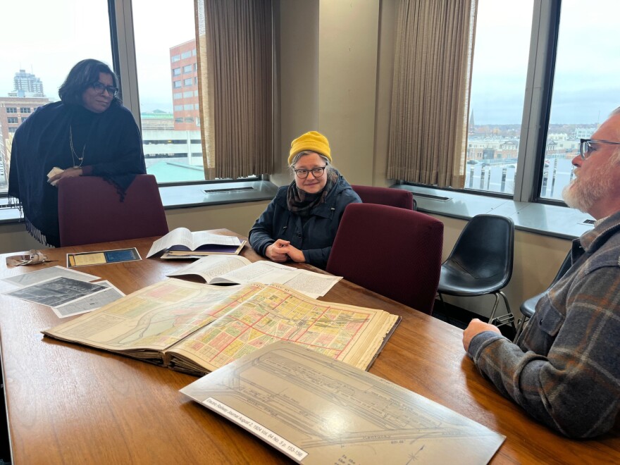 Deputy Mayor Judith Thomas, historian DeeDee Davis and archaeologist Ryan Peterson look at archival records.