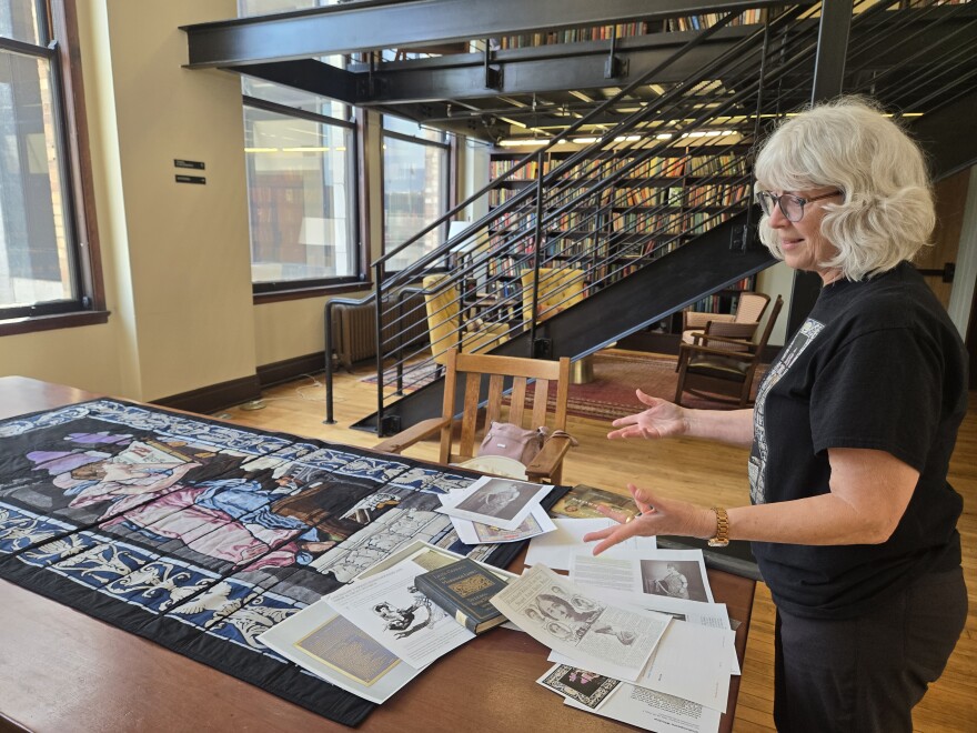 Historian Katherine Durack shows off a quilt she made inspired by a missing stained glass window once housed in the Mercantile Library. The window picturing a woman reading was commissioned by noted Ohio suffragist Augustine "Gussie" Ogden in 1904. It was partially a tribute to her late husband — but also a nod to the Mercantile's connections to the women's rights movement. The whereabouts of the window and another arts-themed one are currently unknown.