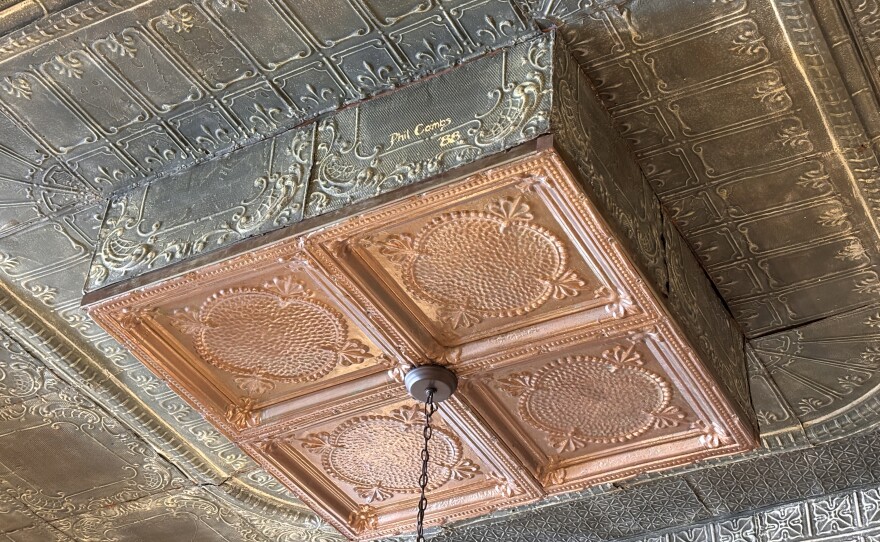 A previous owner, Jerry Thomas, restored many of the Main Street buildings in Fair Grove, including ceilings featuring intricate pressed-tin designs with names and dates painted on (photo taken April 2026).