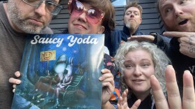 A group of people pose behind a vinyl record.