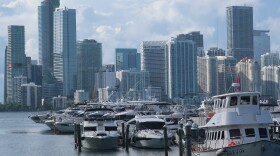 Many boats at a marina are in the foreground, and in the background, the Miami skyline.